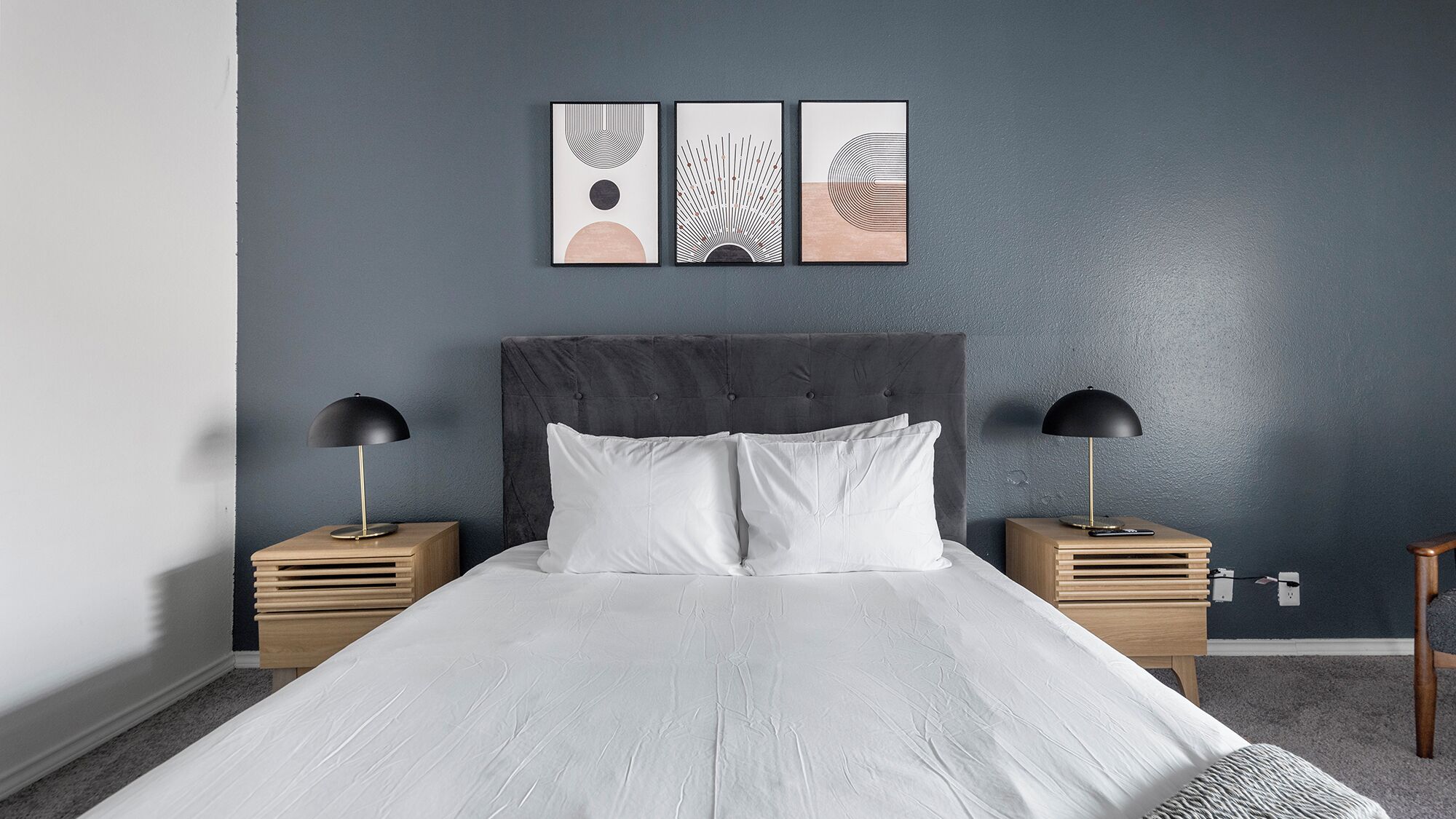 Ein Schlafzimmer mit einem Bett, zwei Nachttischen, einer Kopfteil und drei Wandbildern.