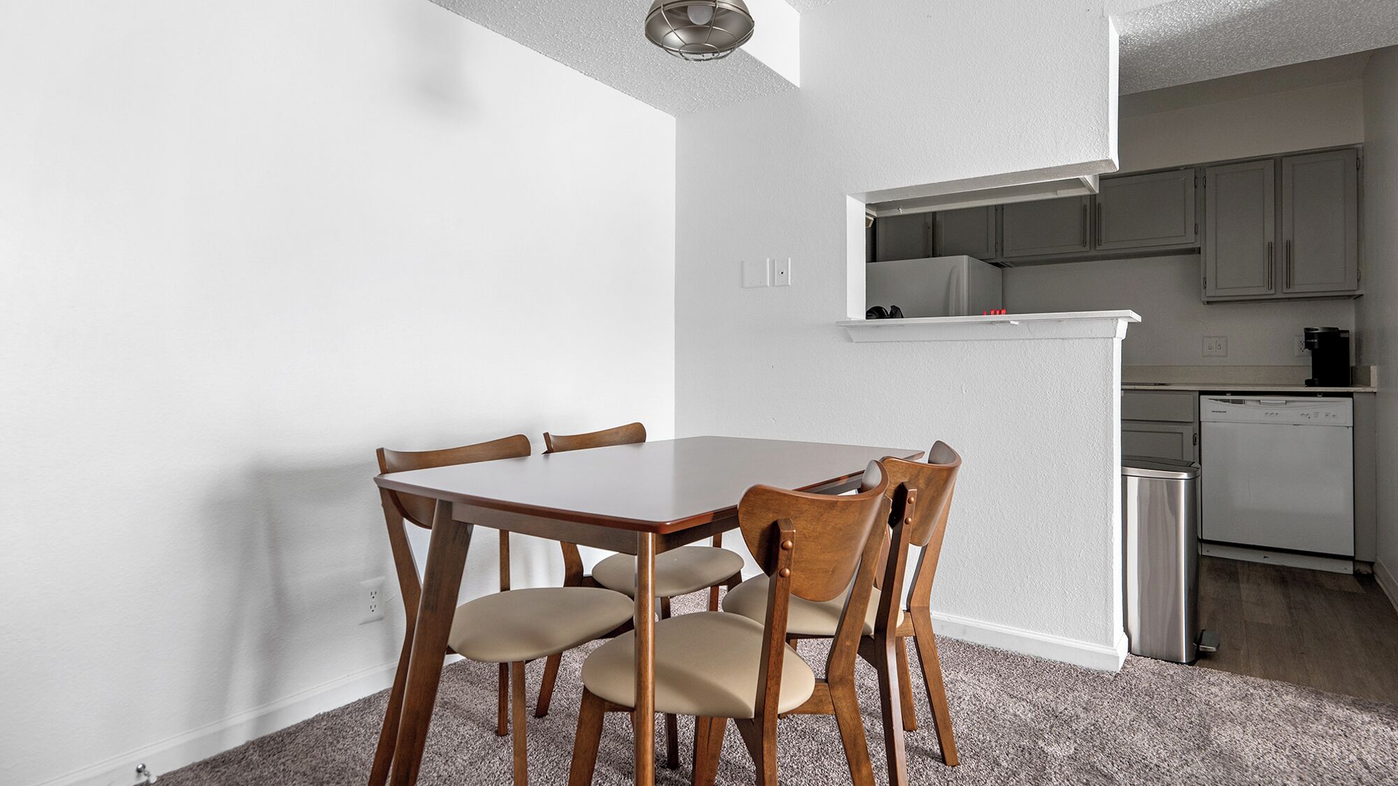 A compact kitchen with white cabinets, a built-in dishwasher, and a small countertop.