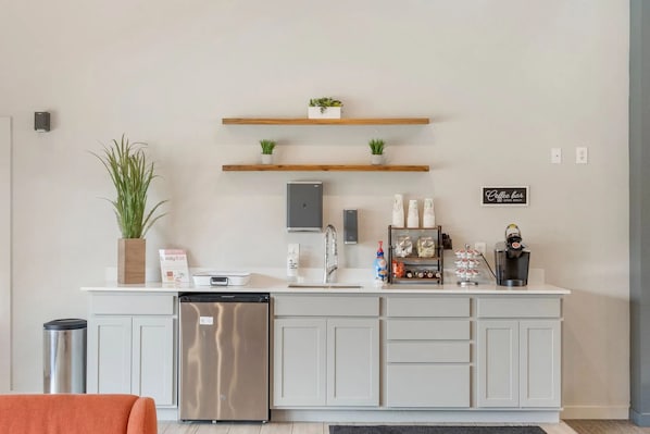 Una cocina moderna con lavavajillas integrado, una zona de café y plantas decorativas.