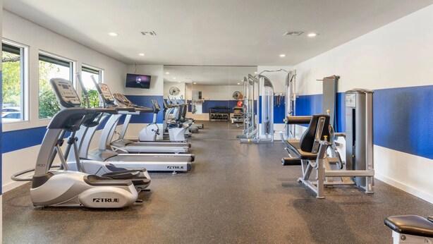 A gym with treadmills, ellipticals, and weight machines. - Landing Tulsa near Woodland (Tulsa)