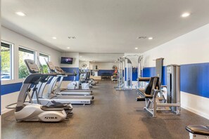 A gym with treadmills, weight machines, and a TV screen.