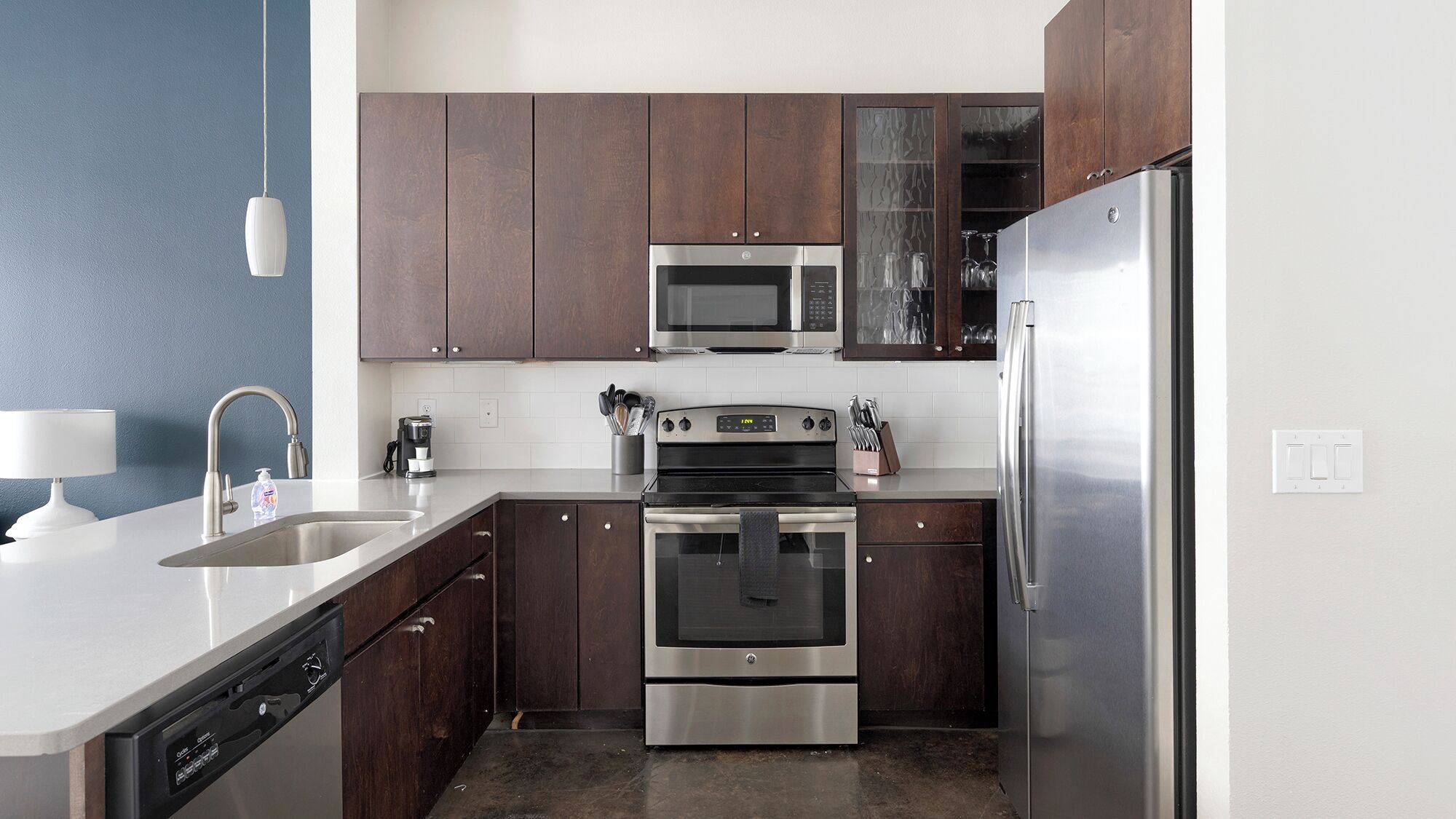 Una cocina moderna con electrodomésticos de acero inoxidable, lavavajillas y armarios de madera oscura.