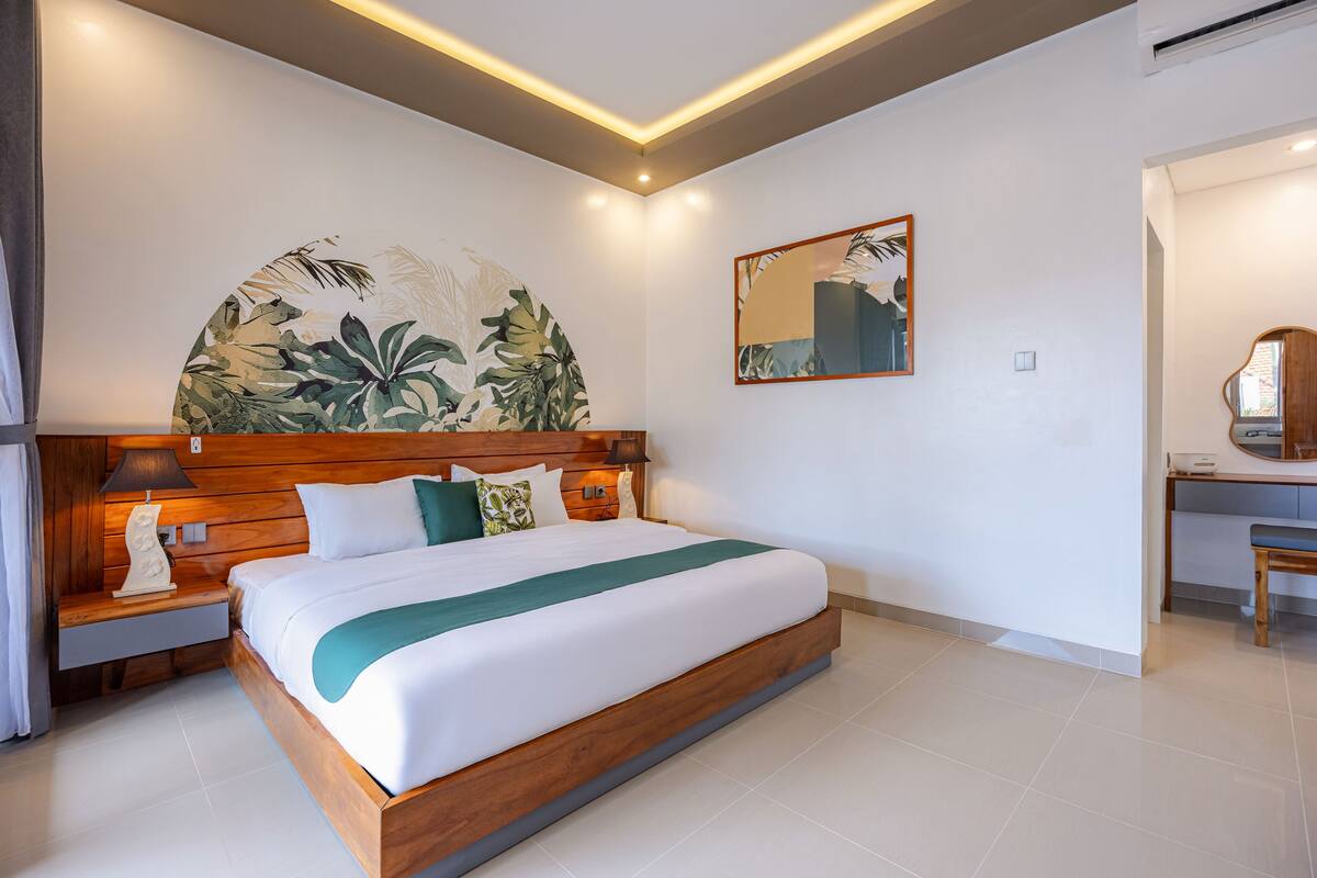 Ein modernes Hotelzimmer mit einem großen Bett, einem Holzkopfende und einem an der Wand befestigten Kunstwerk.