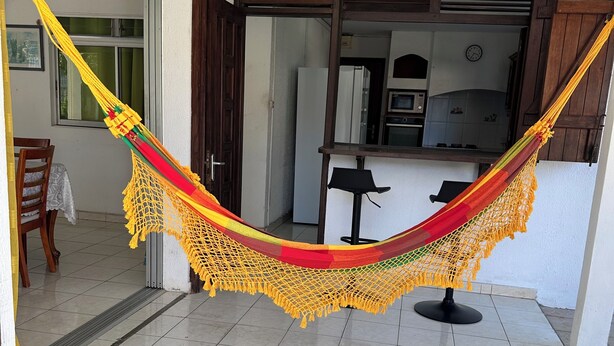 A hammock in a room with a tiled floor, a door, and a view of a kitchen area. - Comfortable Villa with Terrace and Garden – Baie-Mahault Destreland (Baie-Mahault)