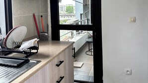 Una cocina moderna con armarios de madera, una encimera y vistas de la ciudad a través de un ventanal abierto.