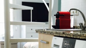 Un'area lavanderia moderna con lavatrice, asciugatrice e un piano di lavoro con macchina per il caffè.