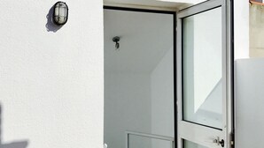 Un edificio bianco con una porta in vetro e una piccola finestra.