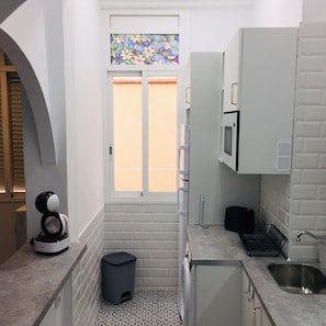 A compact kitchen with a microwave, a small trash bin, and a sink.