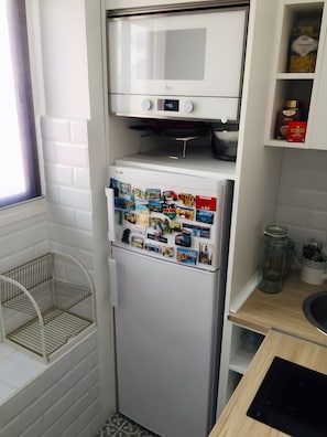Une cuisine compacte équipée d’un réfrigérateur, d’un four à micro-ondes et d’une petite fenêtre.