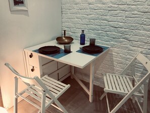 A white table with two black plates, a blue bottle, and a glass.