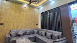 Egy modern nappali, melyben egy moduláris kanapé, egy márvány kávézóasztal és egy mennyezeti ventilátor található.