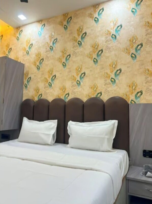A hotel room with a bed, a headboard, a wardrobe, and a nightstand. - Sunaina Palace (Varanasi)