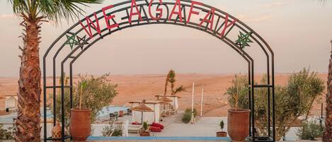 An archway with the text "WE AGAFAI" and palm trees in the foreground.