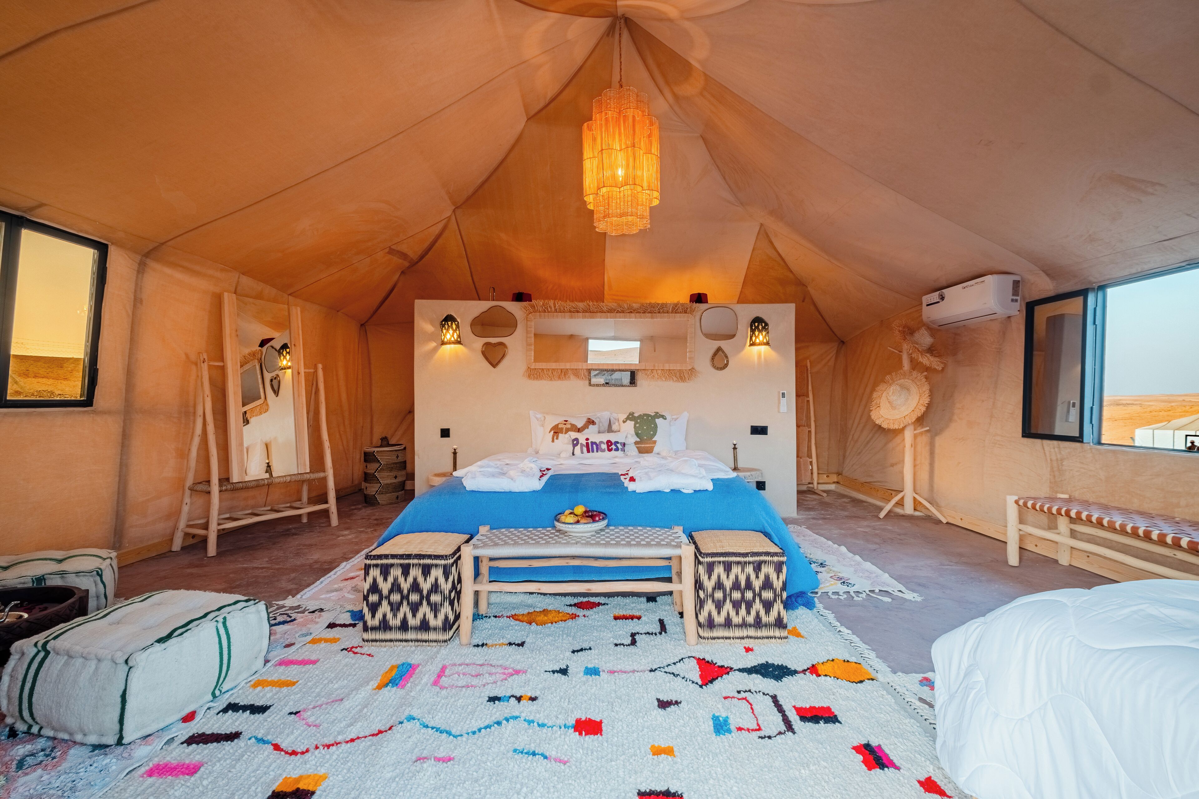 A tented room with a bed, bedside table, and a hanging light fixture.