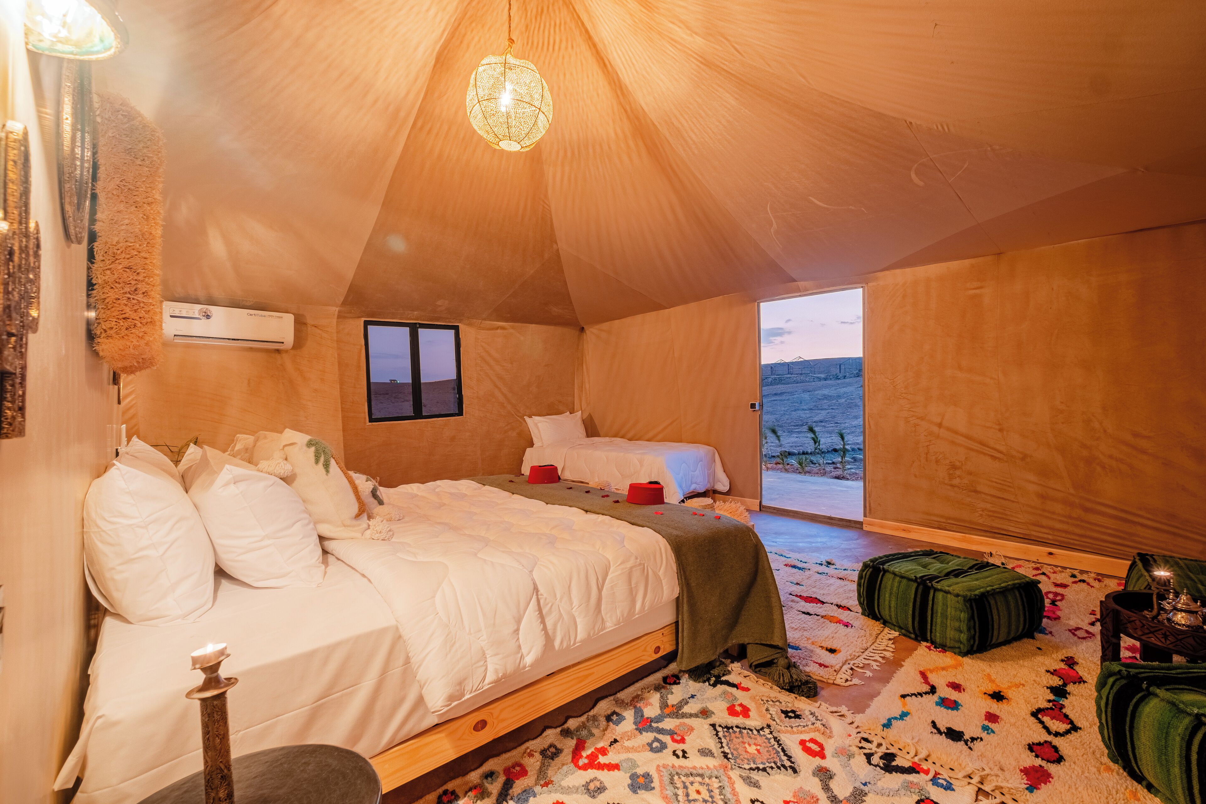 A cozy tent-style room with a bed, a small table, and a view of the outdoors.