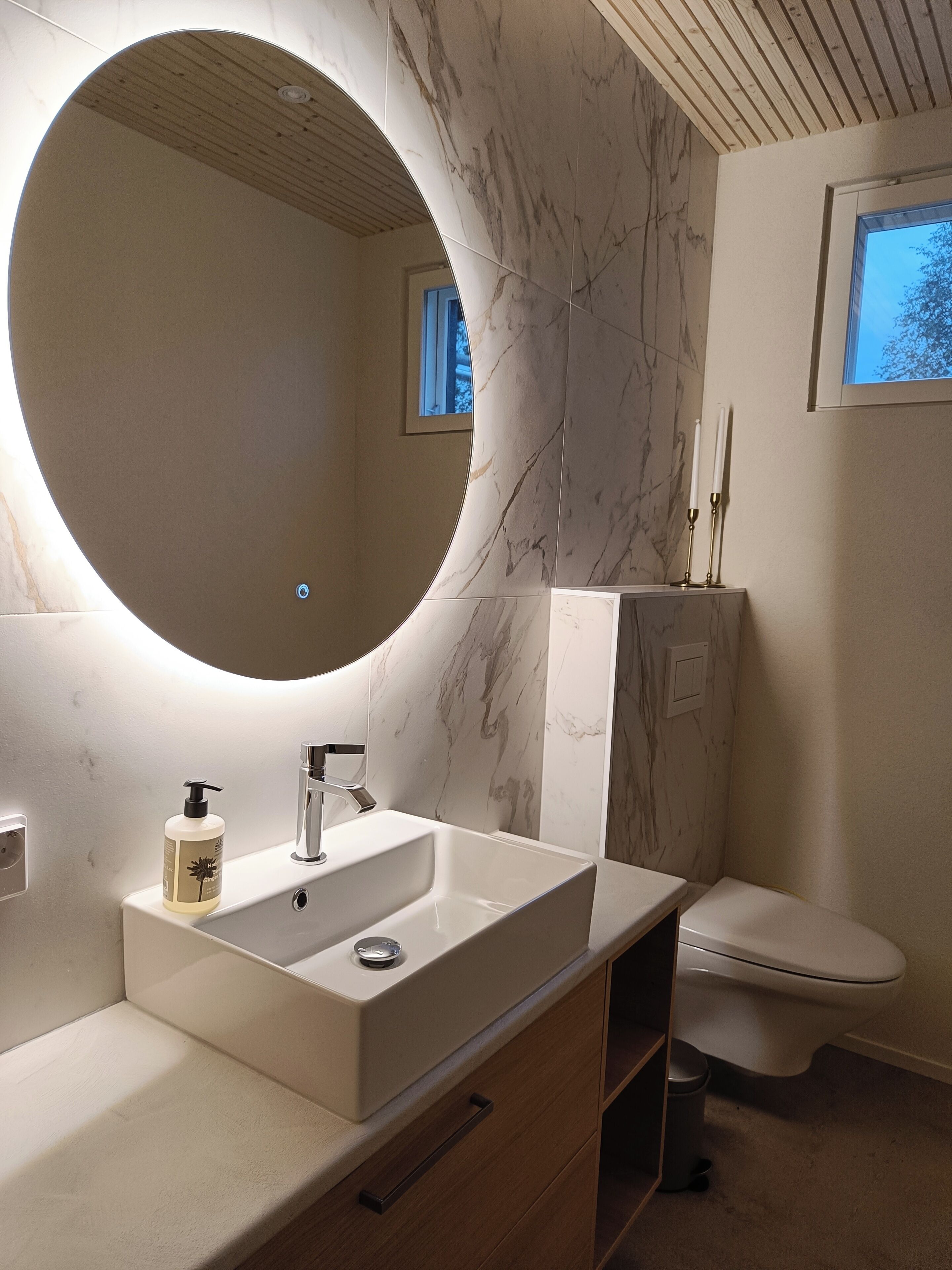Une salle de bain moderne avec un grand miroir, un lavabo et des toilettes.