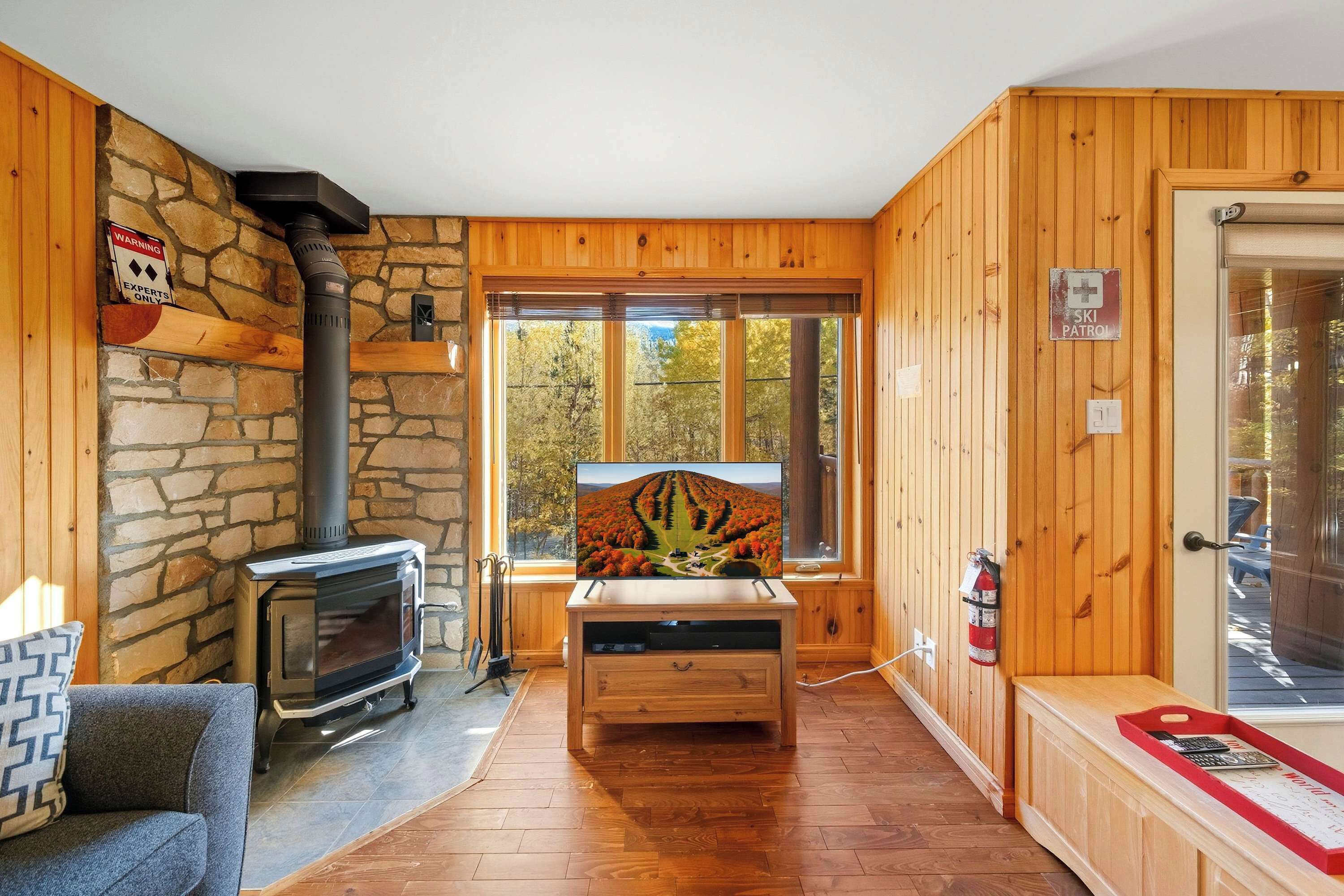 Ein gemütliches Cabin-Interieur mit einer Steinwand, Holzwänden, einem Kamin, einem Fernseher und einem Schild der Skiregierung.