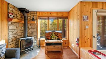 Ein gemütliches Cabin-Interieur mit einer Steinwand, Holzwänden, einem Kamin, einem Fernseher und einem Schild der Skiregierung.