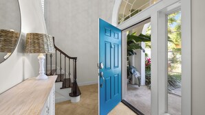 A hallway with a blue door, a staircase, and a mirror. - 4BR Pool Game Room | Good Morning Rentals (Jacksonville Beach)