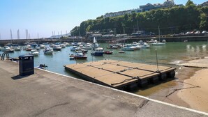 Un port de plaisance avec des bateaux amarrés, une plateforme en béton et un bâtiment en arrière-plan.