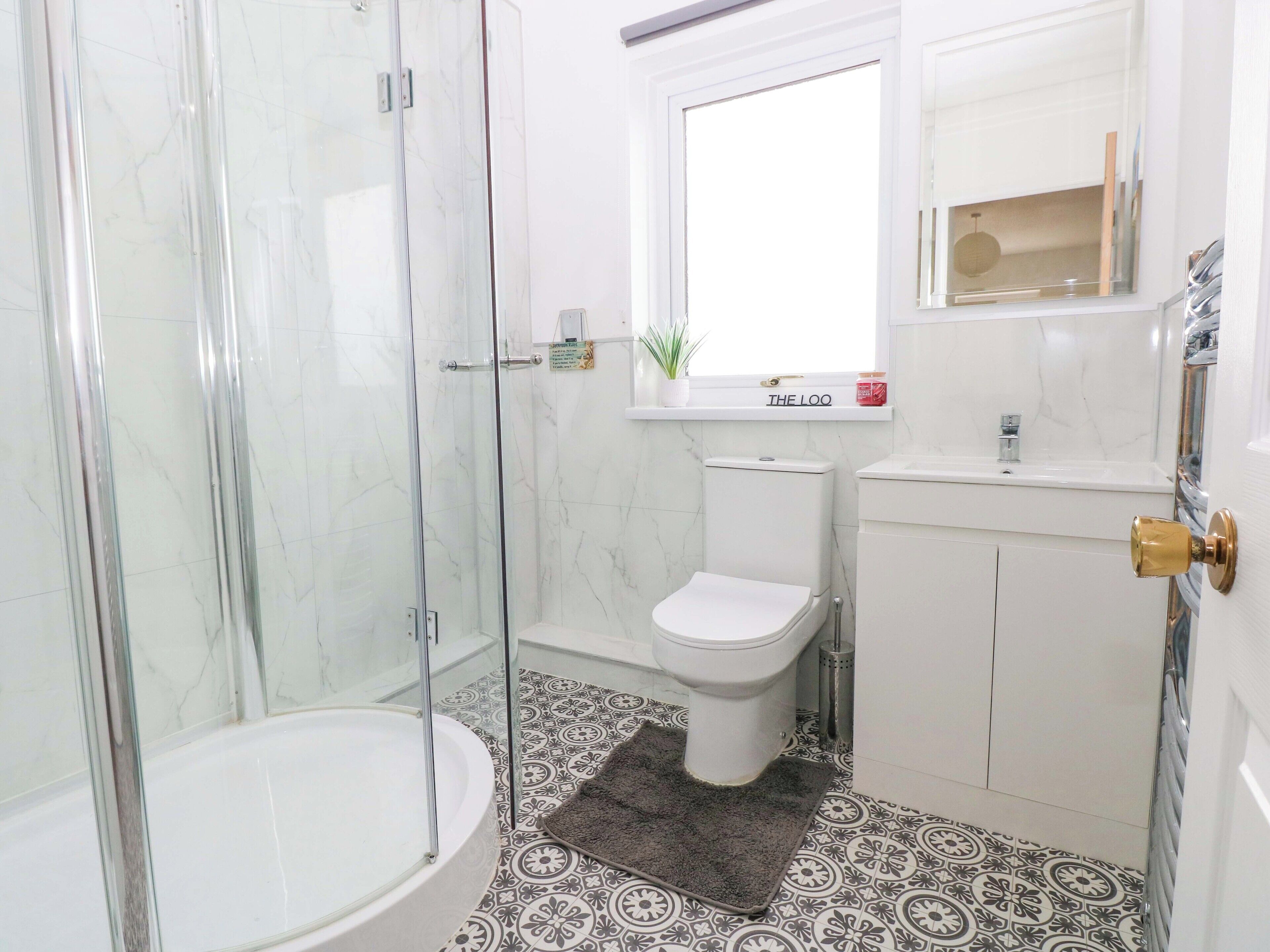 A bathroom with a glass-enclosed shower, a toilet, a sink, and a bathtub.