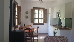 A compact kitchen with a dining area, a washing machine, and a microwave. - Esperanza's little house (Aracena)