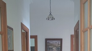 A hallway with wooden doors, a hanging light fixture, and a framed picture on the wall. - Esperanza's little house (Aracena)