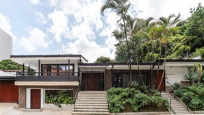 Une maison moderne à deux étages, dotée d’un balcon, d’une porte d’entrée et d’un escalier menant à l’entrée.