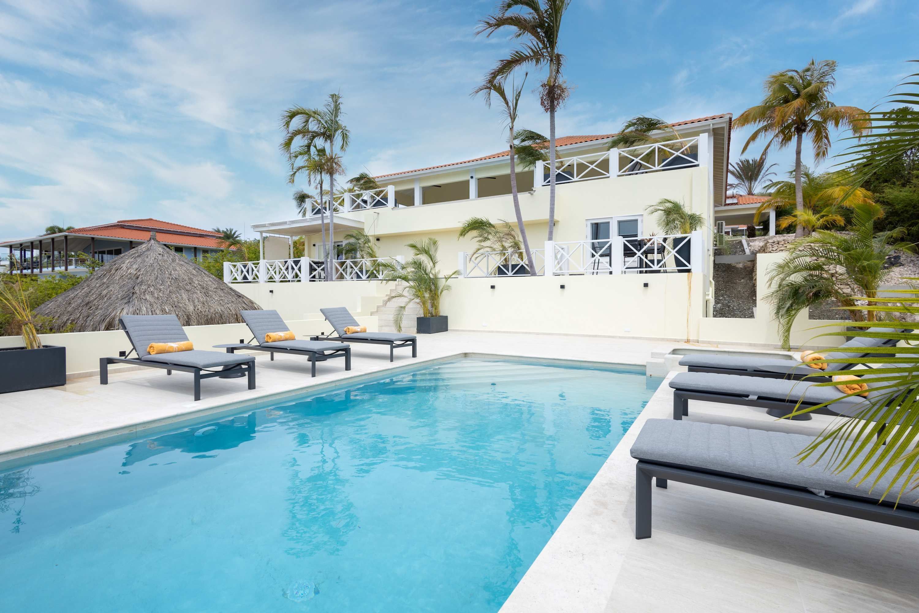 Un espace piscine avec des chaises longues et un bâtiment doté de balcons.