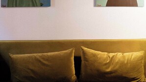 Två inramade konstverk hänger på en vägg ovanför en soffa med två kuddar.