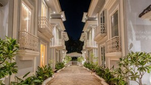 A corridor with a patterned stone floor, flanked by buildings with ornate balconies and a central gate. - Luxury 4bhk Pool Getaway in North Goa Villa Kaia (Valpoy)