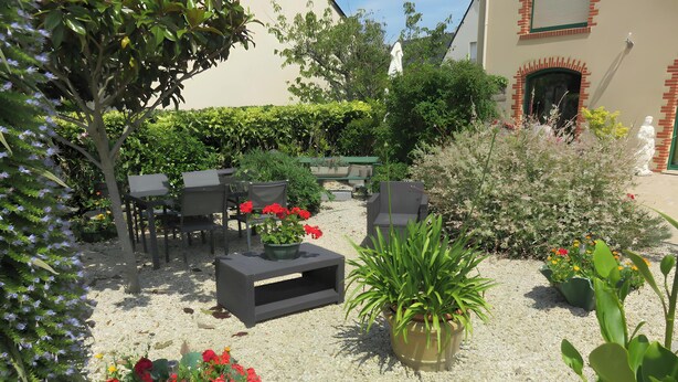 Un jardin avec des sièges extérieurs, une statue et un bâtiment à la façade en briques.