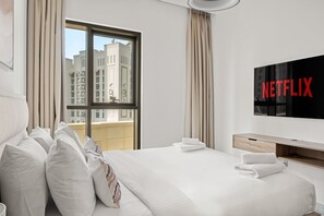 A hotel room with a large bed, a TV mounted on the wall, and a window with a view of buildings. - Creekside 18 A - 103 2BD (Dubai)