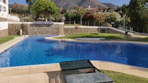 A swimming pool with a stone wall and a view of mountains in the background. - La Casa Bonita (Benalmádena)