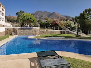 Une piscine avec un mur en pierre et une vue sur les montagnes en arrière-plan.