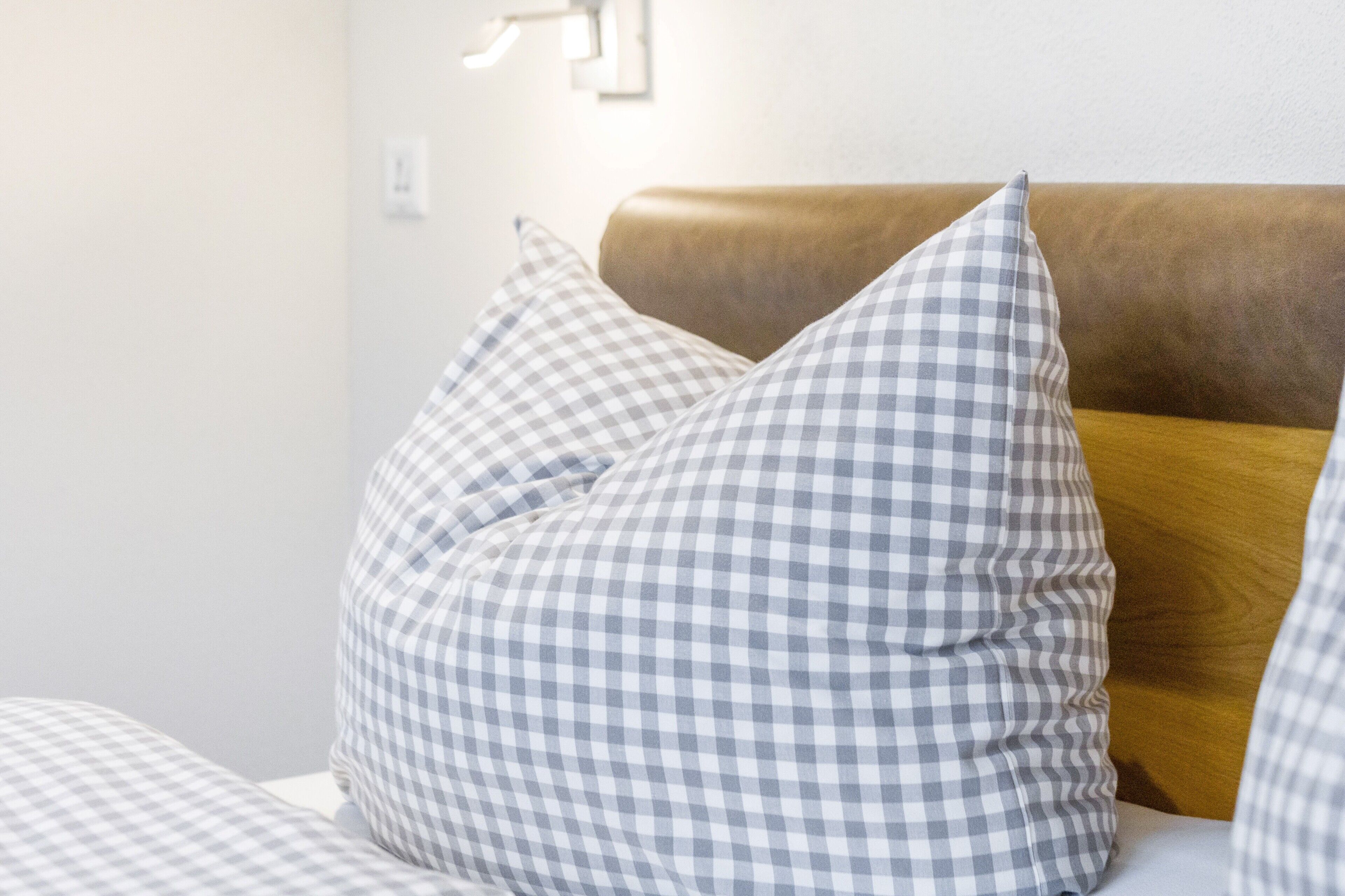 A bed with checkered pillows and a wooden headboard.