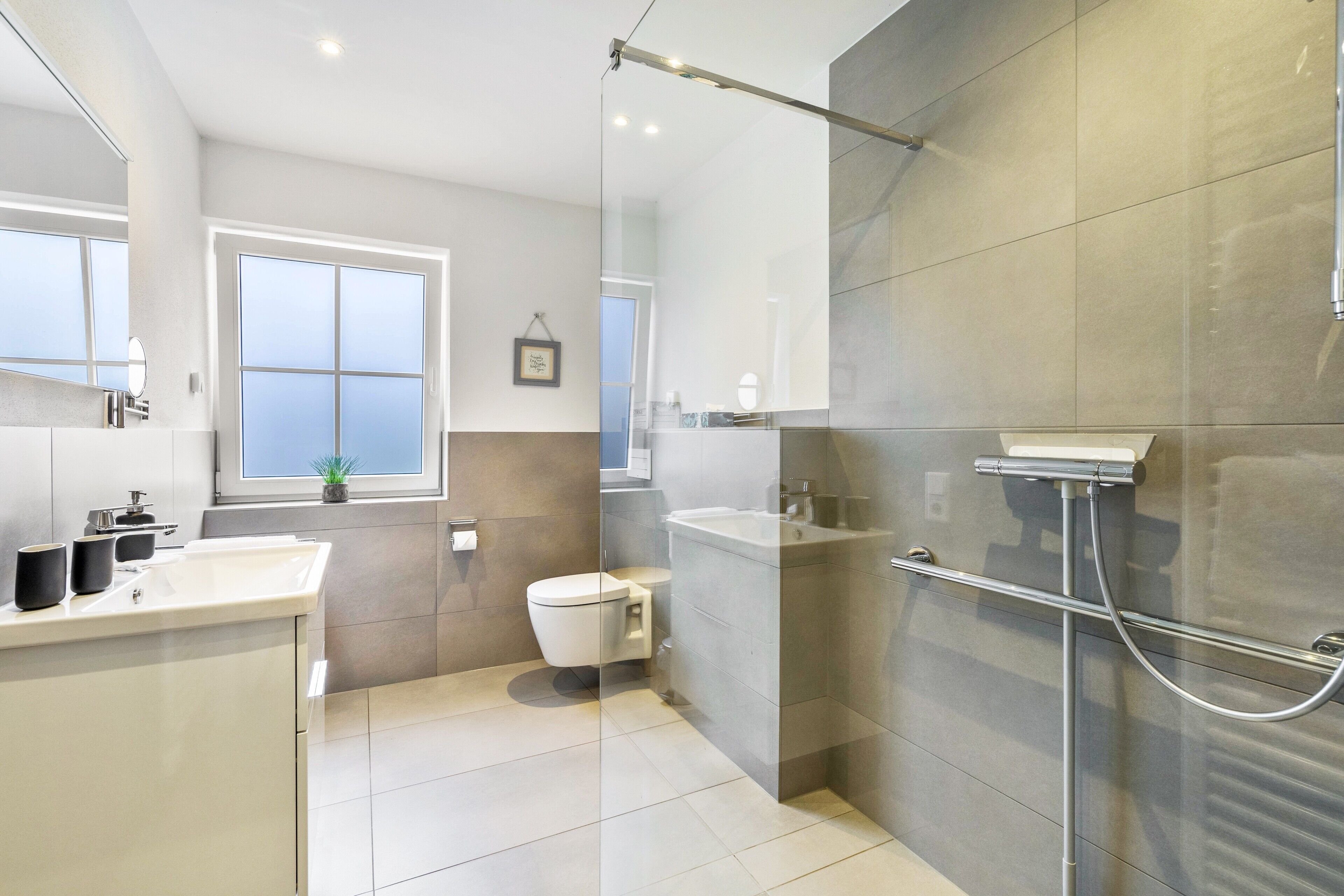 Une salle de bain moderne équipée de toilettes, d’un lavabo et d’un espace douche.