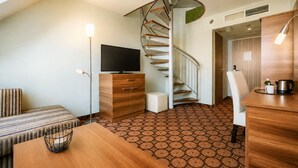 A modern hotel room with a spiral staircase, a flat-screen TV, a wooden dining table, and a patterned floor. - CZECH INN Hotel Ferenc (Budapest)
