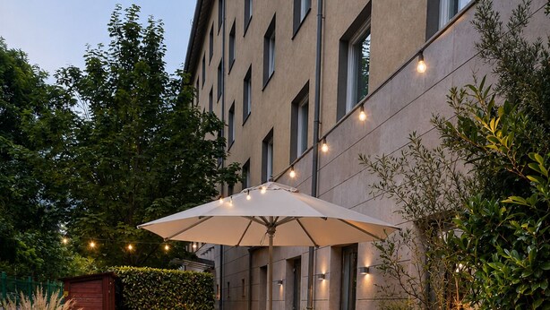 An outdoor patio area with tables and chairs, string lights, and potted plants. - CZECH INN Hotel Ferenc (Budapest)