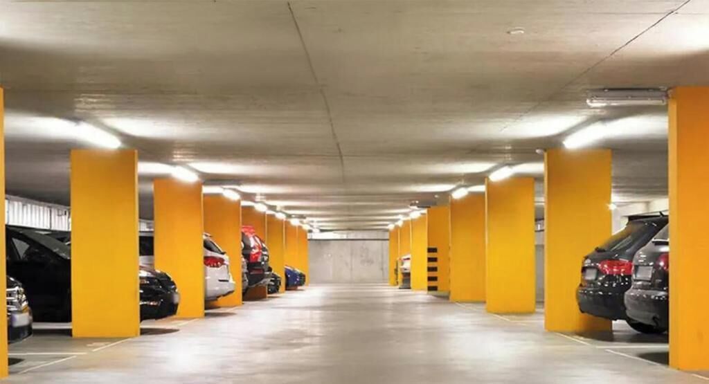 Un estacionamiento con hileras de pilares amarillos y coches aparcados en plazas designadas.
