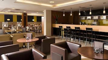 Un restaurant moderne avec des banquettes et des tables rondes, un bar et une cuisine ouverte.