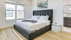 Ein modernes Schlafzimmer mit einem großen Bett, einem Nachttisch, einer Kommode und einem Gemälde an der Wand.