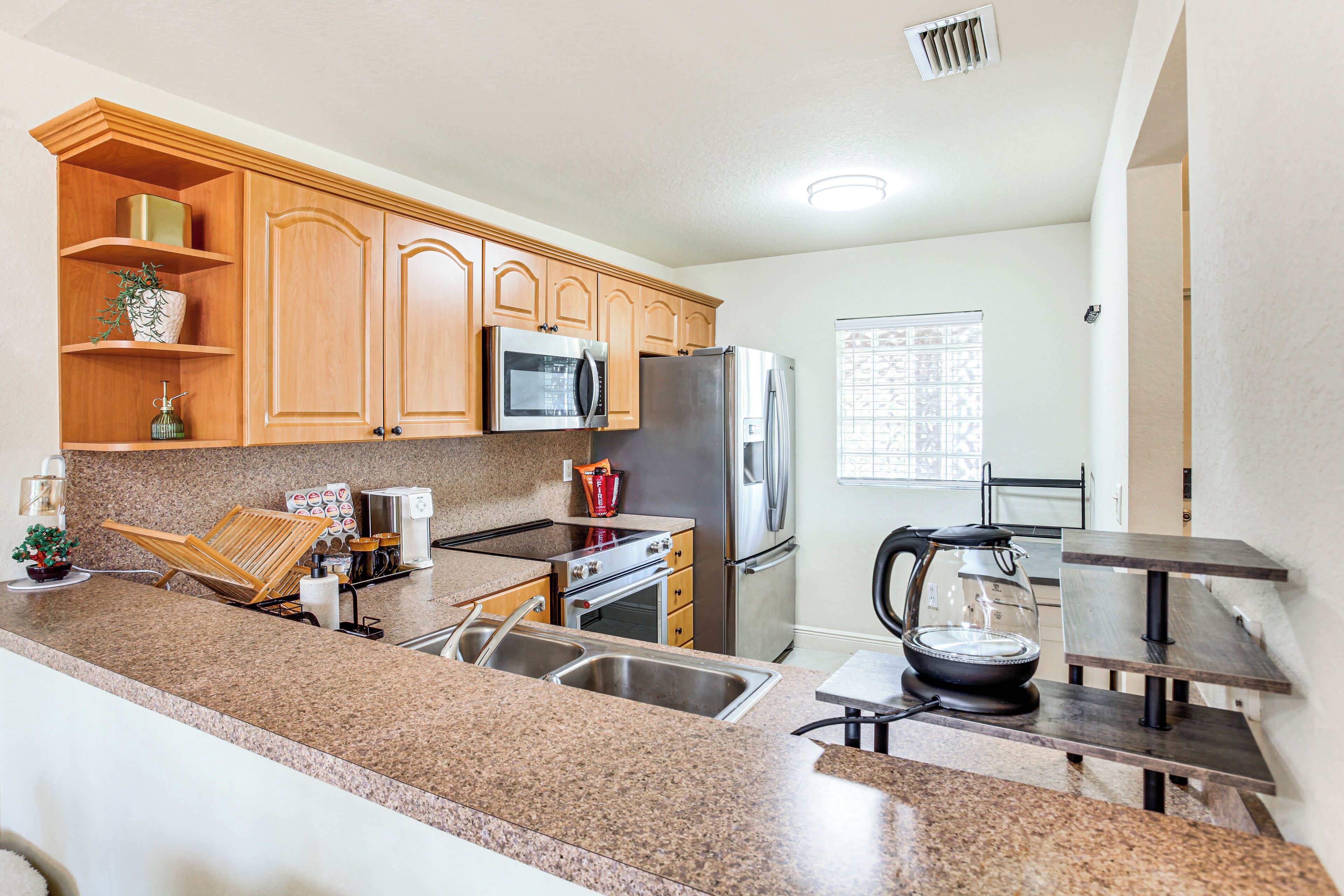 A modern kitchen with granite countertops, stainless steel appliances, wooden cabinets, and a built-in oven.
