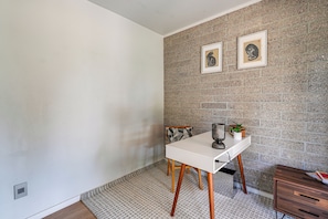 A room with a white table, two framed pictures on the wall, a small plant, and a wooden cabinet. - 1 Mi to Dtwn & Mill Avenue! Home w/ Outdoor Oasis (Tempe)