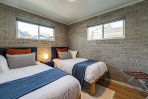 A bedroom with two beds, a nightstand, a lamp, and a window.