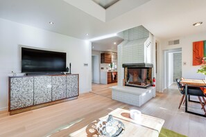 A spacious living area with a flat-screen TV, a fireplace, a dining table with chairs, and a kitchen in the background. - 1 Mi to Dtwn & Mill Avenue! Home w/ Outdoor Oasis (Tempe)