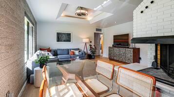 Uma sala de estar moderna com uma mesa de centro de vidro, um sofá e uma lareira.