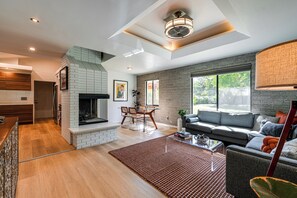 Un salon moderne avec une cheminée, un canapé, un coin repas et une grande fenêtre.