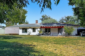 A single-story house with a covered patio, a chimney, and a lawn.