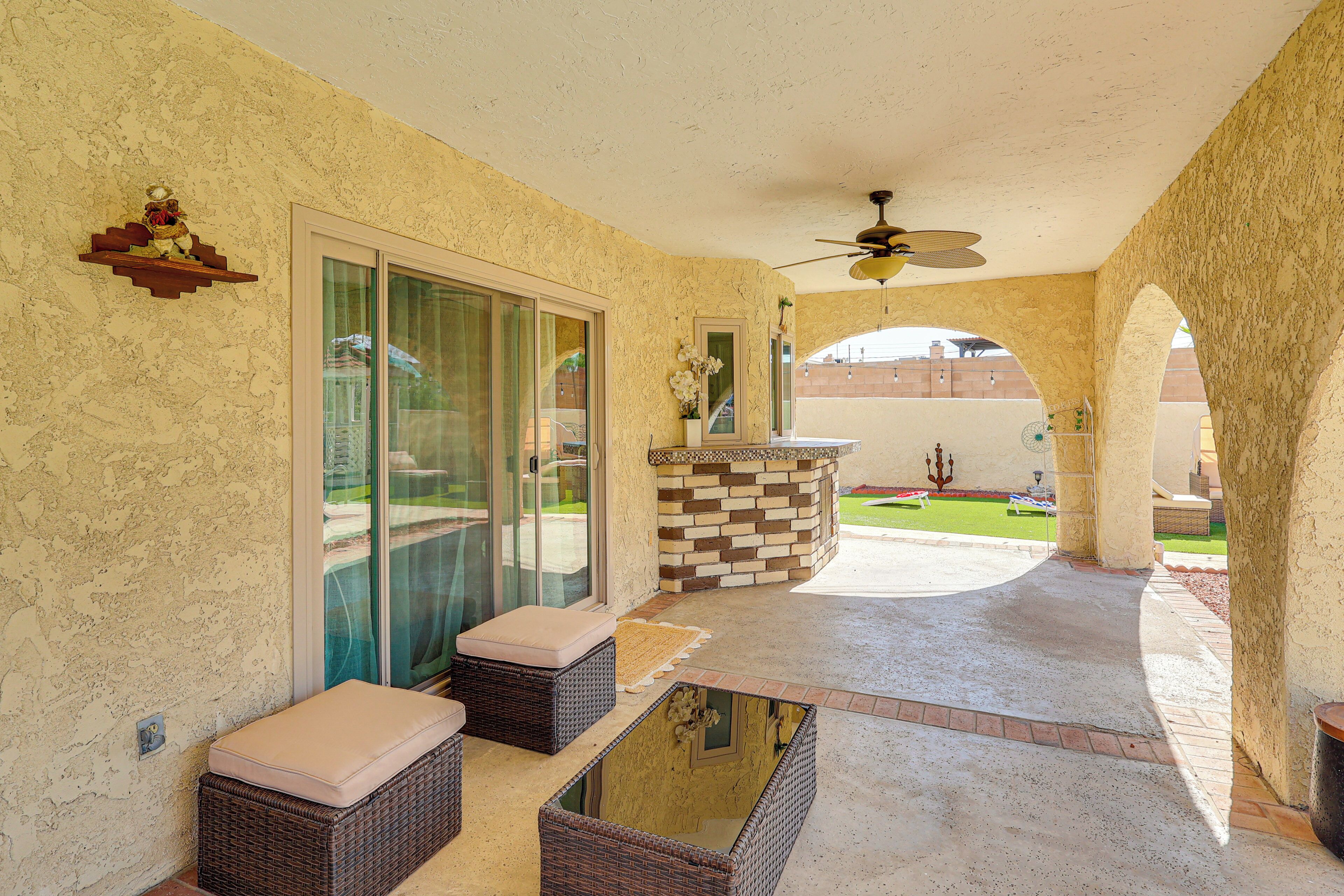 A covered patio with wicker furniture, a glass door leading outside, and a decorative wall.